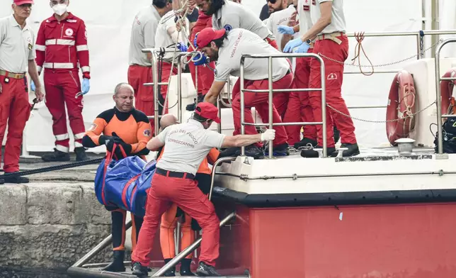 Italian firefighter divers bring ashore in a plastic bag the body of one of the victims of a shipwreck, in Porticello, Sicily, southern Italy, Thursday, Aug. 22, 2024. Divers searching the wreck of the superyacht Bayesian that sank off Sicily on Monday recovered a fifth body on Thursday and continued to search for one more as investigators sought to learn why the vessel sank so quickly. (AP Photo/Salvatore Cavalli)