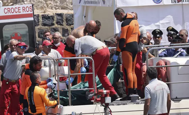 Italian firefighter divers bring ashore in a plastic bag the body of one of the victims of a shipwreck, in Porticello, Sicily, southern Italy, Friday Aug. 23, 2024. Italian rescuers brought ashore the body of the final missing person who was on a superyacht that sunk off the coast of Sicily. (Alberto Lo Bianco/LaPresse via AP)