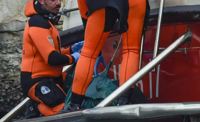 Italian firefighter divers bring ashore in a green bag the body of one of the victims of the UK flag vessel Bayesian, Wednesday, Aug. 21, 2024. The luxury sail yacht was hit by a violent sudden storm and sunk early Monday, while at anchor off the Sicilian village of Porticello near Palermo, in southern Italy. (AP Photo/Salvatore Cavalli)