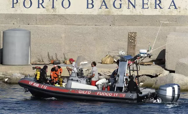 Scuba divers arrive at the harbor of Porticello, southern Italy, Tuesday, Aug. 20, 2024. Rescue teams and divers returned to the site of a storm-sunken superyacht Tuesday to search for six people, including British tech magnate Mike Lynch, who are believed to be still trapped in the hull 50 meters (164-feet) underwater. (AP Photo/Salvatore Cavalli)