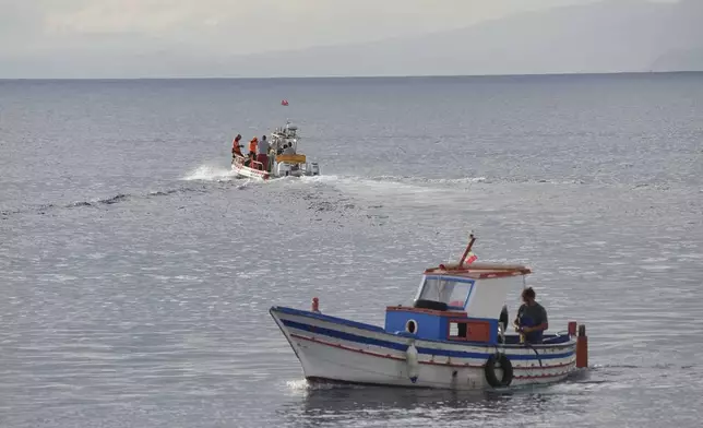 A boat, top, carrying a dive team passes a fishing boat as it heads out to the site of the Bayesian on the fourth day of the search and recovery operation after the luxury yacht sank in a storm on Monday whilst moored around half a mile off the coast of Porticello, Sicily. ( Jonathan Brady/PA via AP)