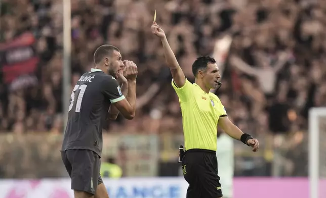 Referee Juan Luca Sacchi gives a yellow card to Milan's Strahinja Pavlovic during the Italian Serie A soccer match between Parma and Milan at Parma's Ennio Tardini Stadium in Parma, Italy, Saturday Aug. 24, 2024. (Massimo Paolone/LaPresse via AP)