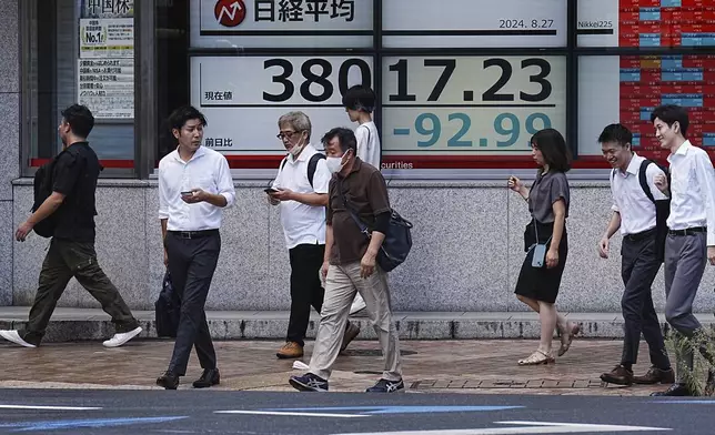 People walk in front of an electronic stock board showing Japan's Nikkei index at a securities firm Tuesday, Aug. 27, 2024, in Tokyo. (AP Photo/Eugene Hoshiko)