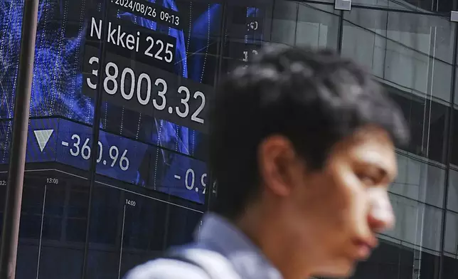 A person walks in front of an electronic stock board showing Japan's Nikkei index at a securities firm Monday, Aug. 26, 2024, in Tokyo. (AP Photo/Eugene Hoshiko)