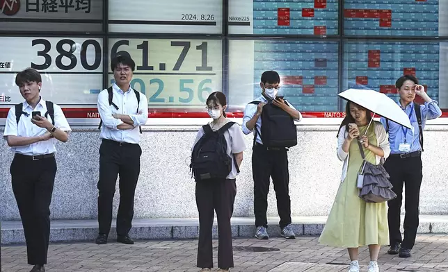 People stand in front of an electronic stock board showing Japan's Nikkei index at a securities firm Monday, Aug. 26, 2024, in Tokyo. (AP Photo/Eugene Hoshiko)