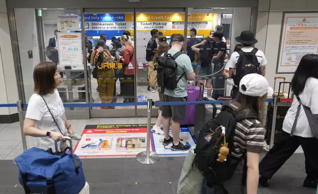 People wait in queue to receive a refund or to change a travel plan on the Shinkansen bullet train bound for westward areas, at Tokyo Station, Friday, Aug. 30, 2024, in Tokyo, after their rides were canceled due to heavy rains caused by a tropical storm. (AP Photo/Eugene Hoshiko)