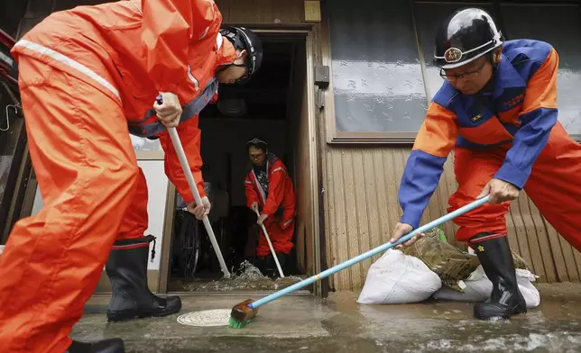 Firefighters help clean up floodwater out of a house in Ogaki, central Japan, Saturday, Aug. 31, 2024, following a tropical storm in the area. (Natsumi Yasumoto/Kyodo News via AP)