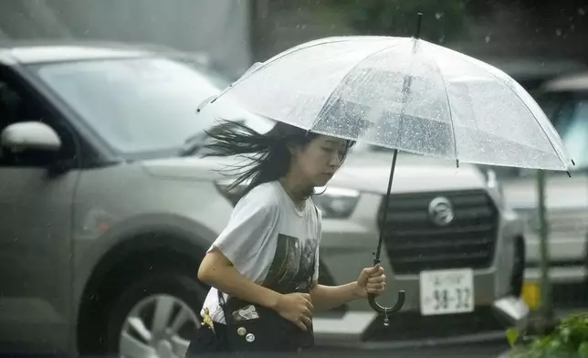 A person walks in the rain Friday, Aug. 30, 2024, in Tokyo, as a severe weather system has affected. (AP Photo/Eugene Hoshiko)