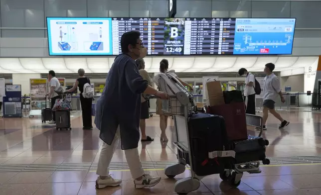 Passengers look at flight information as some flights were canceled due to a severe weather system affecting Japan, at Haneda airport Friday, Aug. 30, 2024, in Tokyo. (AP Photo/Eugene Hoshiko)