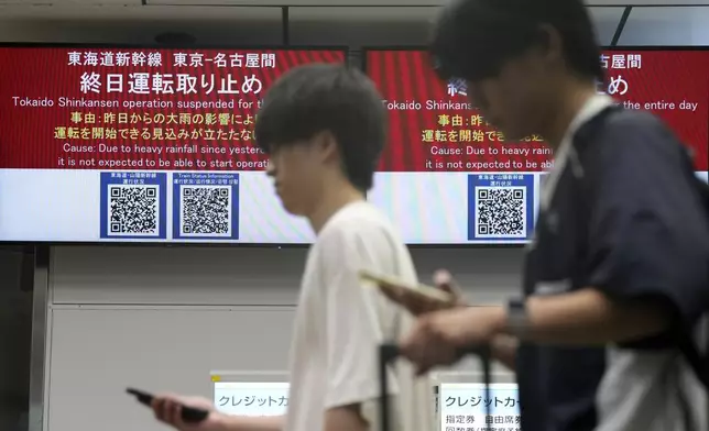 People walk past notices that all trains of Tokaido and Sanyo Shinkansen toward Nagoya or westward are canceled due to heavy rainfall caused by Typhoon Shanshan at the Tokyo Station, Friday, Aug. 30, 2024, in Tokyo. (AP Photo/Eugene Hoshiko)