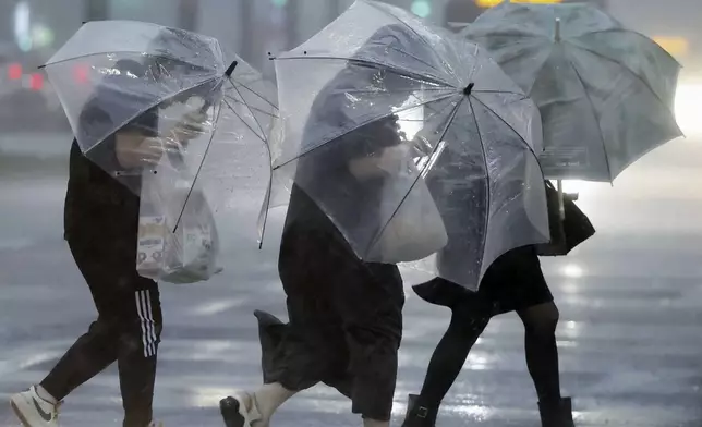 People holding umbrella, struggle with the heavy rain as a typhoon is approaching in Kagoshima, western Japan, Wednesday, Aug. 28, 2024, (Hidetaka Komukai/Kyodo News via AP)