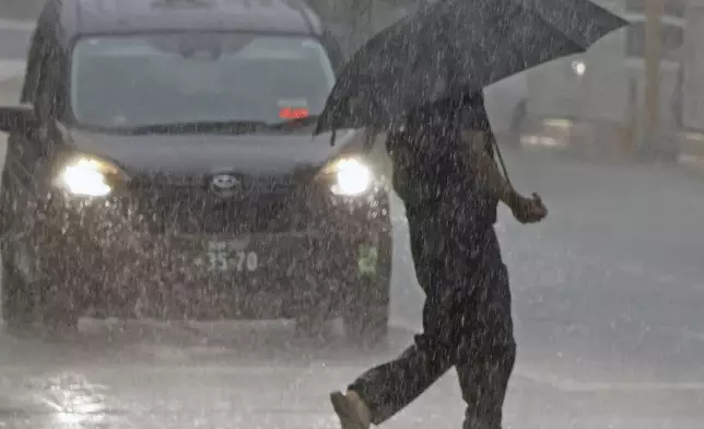 People holding an umbrella crosses a street in the heavy rain in Miyazaki, Miyazaki prefecture, western Japan, Wednesday, Aug. 28, 2024, as a typhoon is approaching. (Kyodo News via AP)