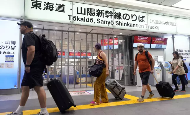 Travelers walk past the closed gate for Tokaido and Sanyo Shinkansen lines as all trains toward to Nagoya or westward are suspended due to heavy rainfall caused by Typhoon Shanshan at the Tokyo Station, Friday, Aug. 30, 2024, in Tokyo. (AP Photo/Eugene Hoshiko)