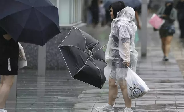 People holding umbrella, struggles with the strong wind as a typhoon is approaching in Fukuoka, western Japan, Thursday, Aug. 29, 2024. (Kyodo News via AP)