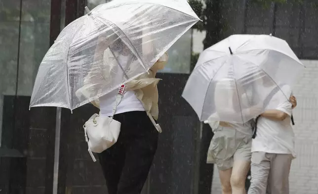 People holding umbrella, struggle with the strong wind as a typhoon is approaching in Fukuoka, western Japan, Thursday, Aug. 29, 2024. (Kyodo News via AP)