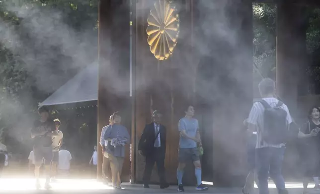 People walk through a gate to the main hall of the Yasukuni Shrine, which honors Japan's war dead, in Tokyo, Japan, Thursday, Aug. 15, 2024, as the country marks the 79th anniversary of its defeat in the World War II. (AP Photo/Hiro Komae)