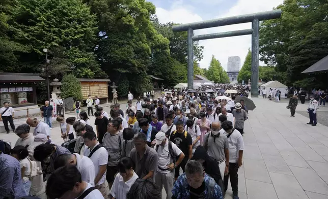 People observe a minute of silence at noon, while waiting in queue before reaching to the main hall to pray at Yasukuni Shrine, which honors Japan's war dead, in Tokyo, Japan, Thursday, Aug. 15, 2024, as the country marks the 79th anniversary of its defeat in the World War II. (AP Photo/Hiro Komae)