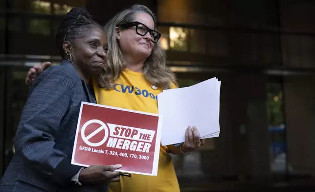 Faye Guenther, president of local UFCW 3000, hugs Carol McMillian, bakery manager at Kroger-owned King Soopers and member of Local 7, after a news conference about the Kroger and Albertsons merger outside the federal courthouse on Monday, Aug. 26, 2024, in Portland, Ore. (AP Photo/Jenny Kane)