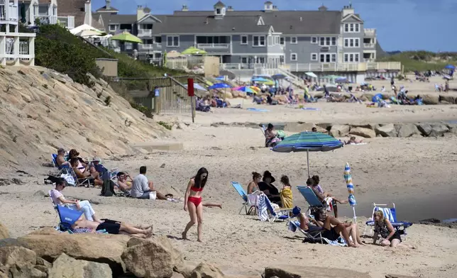 People sit on the beach, Friday, Aug. 30, 2024, in Dennis Port, Mass. (AP Photo/Michael Dwyer)