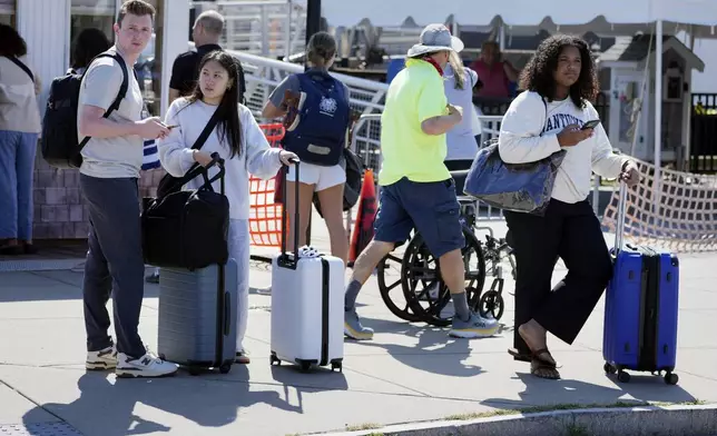 Travelers wait for ride shares after disembarking the ferry from Nantucket Island, Friday, Aug. 30, 2024, in Hyannis, Mass. (AP Photo/Michael Dwyer)