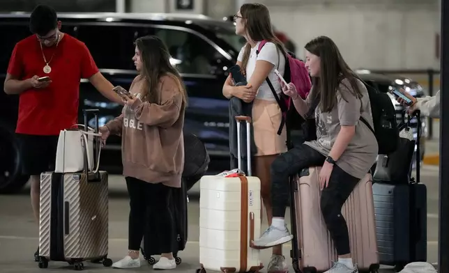 Travelers wait for their ride share vehicles at the Nashville International Airport, Friday, Aug. 30, 2024, in Nashville, Tenn. (AP Photo/George Walker IV)