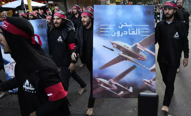 Members of Iranian-backed Hezbollah group walk barefoot as they carry a poster showing Hezbollah drones that read, in Arabic: "We are coming," during the holy day of Ashoura, which commemorates the 7th century martyrdom of the Prophet Muhammad's grandson Hussein, in the southern suburb of Beirut, Lebanon, Tuesday, Aug. 9, 2022. (AP Photo/Hussein Malla, File)