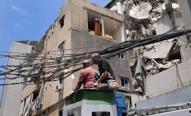 Municipality workers remove power cables in front of damaged buildings that were hit by an Israeli airstrike on Tuesday evening in a southern suburb of Beirut, Lebanon, Wednesday, July 31, 2024. (AP Photo/Hussein Malla)