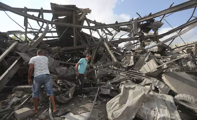 Men inspect an industrial area destroyed by an Israeli airstrike, in Wadi al-Kfour, Nabatieh province, south Lebanon, Saturday, Aug. 17, 2024. (AP Photo/Mohammed Zaatari)