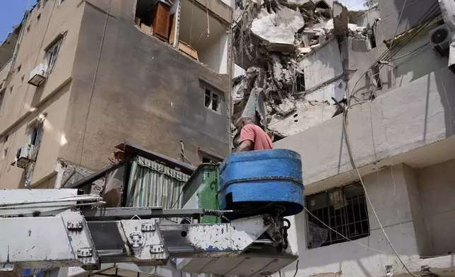 A municipality worker stands on a man lift in front of damaged buildings that were hit by an Israeli airstrike on Tuesday evening in a southern suburb of Beirut, Lebanon, Wednesday, July 31, 2024. (AP Photo/Hussein Malla)