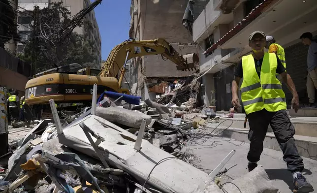 A municipality worker walks by debris as a backhoe removes rubbles from a building that was damaged by an Israeli airstrike on Tuesday evening in a southern suburb of Beirut, Lebanon, Wednesday, July 31, 2024. (AP Photo/Hussein Malla)