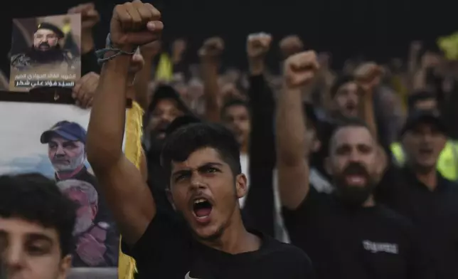 Supporters raise their fists and cheer as they watch a speech given by Hezbollah leader Sayyed Hassan Nasrallah on a screen during a ceremony to commemorate the death of top commander Fouad Shukur, who was killed by an Israeli airstrike last week, in Beirut, Lebanon, Tuesday, Aug. 6, 2024. (AP Photo/Mustafa Jamalddine)