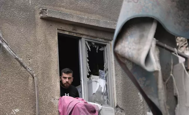 A man looks through a broken window at building that was damaged by an Israeli airstrike on Tuesday evening in a southern suburb of Beirut, Lebanon, Wednesday, July 31, 2024. Israel on Tuesday carried out a rare strike on Beirut, which it said killed a top Hezbollah commander who was allegedly behind a weekend rocket attack that killed 12 young people in the Israeli-controlled Golan Heights. (AP Photo/Hussein Malla)