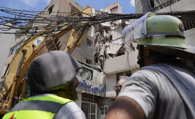 Hezbollah civil defense workers stand in front a building that was destroyed by an Israeli airstrike on Tuesday evening in a southern suburb of Beirut, Lebanon, Wednesday, July 31, 2024. (AP Photo/Hussein Malla)