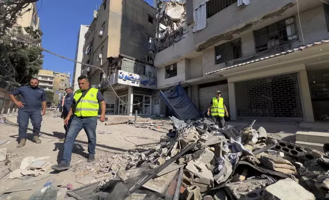 Municipality workers pass by debris of damaged buildings that were hit by an Israeli airstrike on Tuesday evening in the southern suburbs of Beirut, Lebanon, Wednesday, July 31, 2024. Israel on Tuesday carried out a rare strike on Beirut, which it said killed a top Hezbollah commander who was allegedly behind a weekend rocket attack that killed 12 young people in the Israeli-controlled Golan Heights. (AP Photo/Hussein Malla)