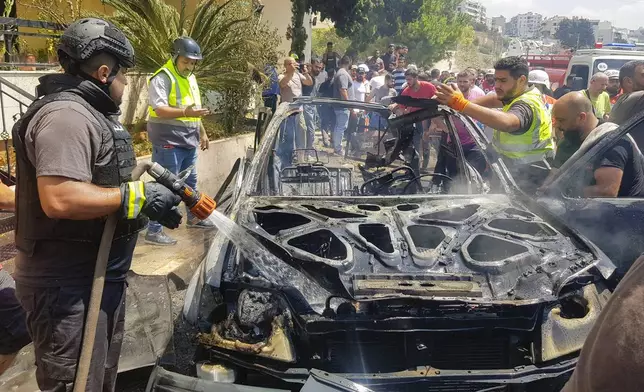 Civil Defense workers inspect the remains of a burned car that was hit by an Israeli strike in the southern port city of Sidon, Lebanon, Monday, Aug. 26, 2024. (AP Photo/Mohammed Zaatari)