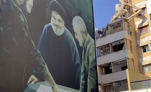 A poster showing the late Hezbollah military commander Imad Mughniyeh, left, Hezbollah leader Sayyed Hassan Nasrallah, center, and the late Revolutionary Guard Gen. Qassem Soleimani is set near a damaged building that was hit by an Israeli airstrike on Tuesday evening in the southern suburbs of Beirut, Lebanon, Wednesday, July 31, 2024. Israel on Tuesday carried out a rare strike on Beirut, which it said killed a top Hezbollah commander who was allegedly behind a weekend rocket attack that killed 12 young people in the Israeli-controlled Golan Heights. (AP Photo/Hussein Malla)