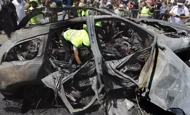 Civil Defense workers look for human remains inside a car that was hit by an Israeli strike in the southern port city of Sidon, Lebanon, Wednesday, Aug. 21, 2024. (AP Photo/Mohammed Zaatari)