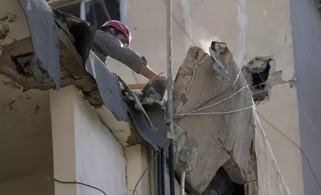 A civil defense worker removes wreckage from a roof top of a building that was damaged by an Israeli airstrike on Tuesday evening in a southern suburb of Beirut, Lebanon, Wednesday, July 31, 2024. (AP Photo/Hussein Malla)