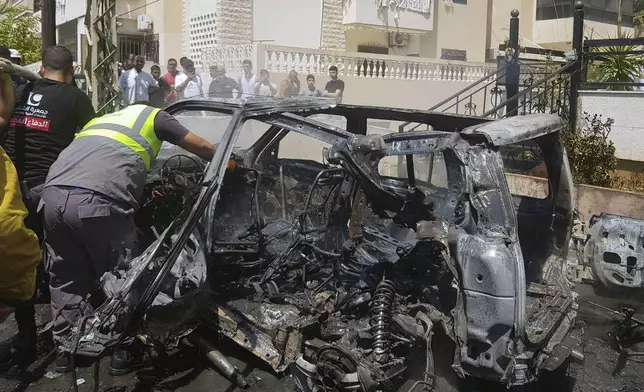 A Civil Defense worker inspects the remains of a burned car that was hit by an Israeli strike in the southern port city of Sidon, Monday, Aug. 26, 2024. After a short-lived calm following a heavy exchange of strikes between Israel and the Lebanese militant group Hezbollah, fighting resumed Monday. (AP Photo/Mohammed Zaatari)