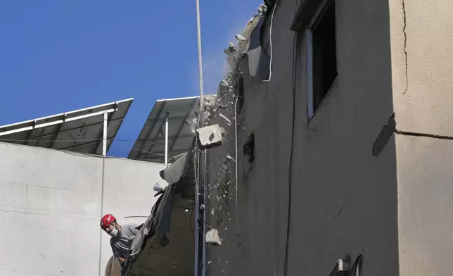 A civil defense worker removes wreckage from a roof top of a building that was damaged by an Israeli airstrike on Tuesday evening in a southern suburb of Beirut, Lebanon, Wednesday, July 31, 2024. (AP Photo/Hussein Malla)