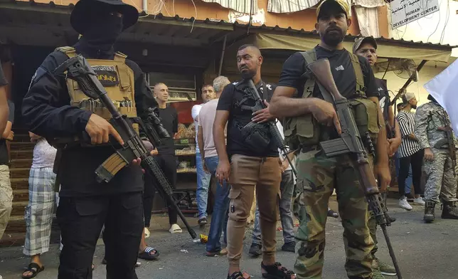 Palestinian Fatah fighters from Al-Aqsa Martyrs' Brigades, stand guard during the funeral procession of Khalil al-Maqdah, the brother of Fatah Gen. Mounir al-Maqdah, who was killed by an Israeli strike on a vehicle in the southern port city of Sidon, at the Palestinian refugee camp of Ein el-Hilweh, south Lebanon, Wednesday, Aug. 21, 2024. (AP Photo/Mohammed Zaatari)