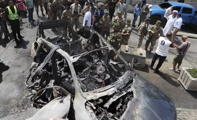 Lebanese army soldiers gather around a car that was hit by an Israeli strike in the southern port city of Sidon, Lebanon, Wednesday, Aug. 21, 2024. (AP Photo/Mohammad Zaatari)