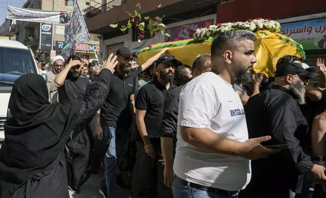 A woman throws rose petals as mourners carry the coffin of Ali Ahmad Mousawi, who was killed early Wednesday by an Israeli strike, during his funeral procession in Nabi Sheet village, in Lebanon's eastern Bekaa Valley, Wednesday, Aug. 21, 2024. (AP Photo/Bilal Hussein)