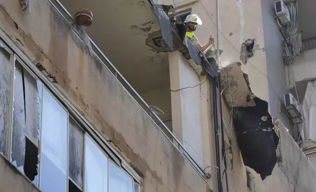 A civil defense worker removes wreckage from a roof top of a building that was damaged by an Israeli airstrike on Tuesday evening in a southern suburb of Beirut, Lebanon, Wednesday, July 31, 2024. (AP Photo/Hussein Malla)