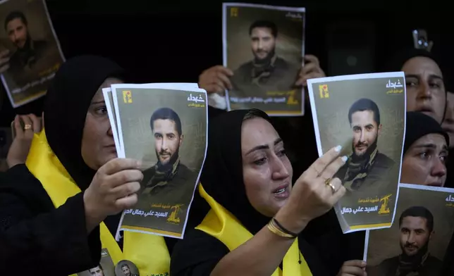 Mourners carry portraits of Hezbollah commander Ali Jawad, who was killed on Monday by an Israeli airstrike, during his funeral procession, in Beirut, Lebanon, Tuesday, Aug. 6, 2024. Since early October, Hezbollah began attacking Israeli military posts along the border calling it a backup front for their Palestinian allies in the Gaza Strip. (AP Photo/Hussein Malla)