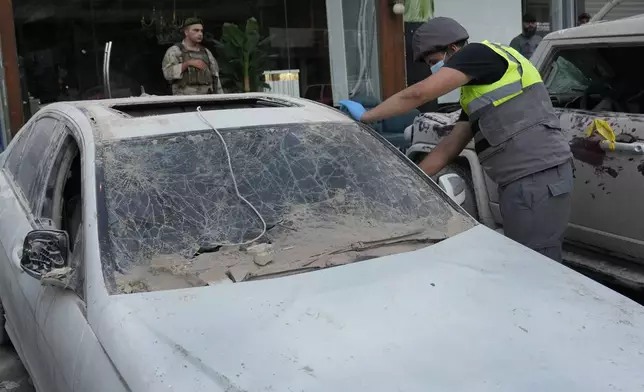 A Hezbollah civil defense worker checks a damaged car at the scene where an Israeli airstrike on Tuesday evening hit a building in the southern suburbs of Beirut, Lebanon, Wednesday, July 31, 2024. (AP Photo/Hussein Malla)