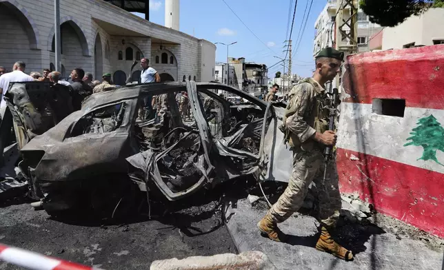 A Lebanese army soldier passes in front a car that was hit by an Israeli strike in the southern port city of Sidon, Lebanon, Wednesday, Aug. 21, 2024. (AP Photo/Mohammad Zaatari)