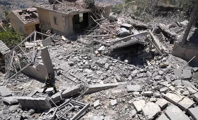 FILE - A civil defense worker inspects destroyed houses that were hit by an Israeli airstrike, in Chebaa, a Lebanese town near the border with Israel, south Lebanon, June 26, 2024. (AP Photo/Hussein Malla, File)