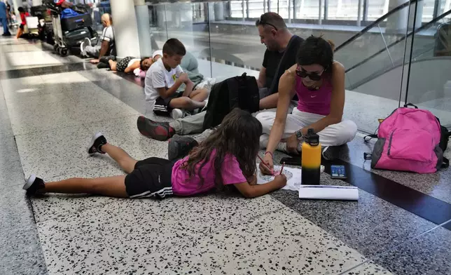 FILE - Passengers whose flights were cancelled sit at the departure terminal ground of Rafik Hariri International Airport in Beirut, Lebanon, Aug. 5, 2024. (AP Photo/Hussein Malla, File)