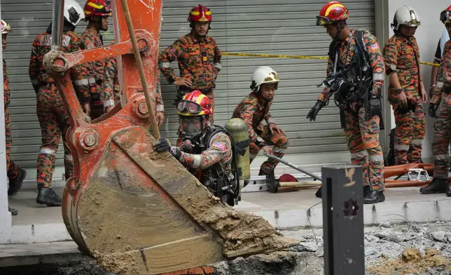 Fire and Rescue department use crane to dig after receiving reports that a woman has fallen into the sinkhole after a section of the sidewalk caved in Kuala Lumpur, Friday, Aug. 23, 2024. (AP Photo/Vincent Thian)